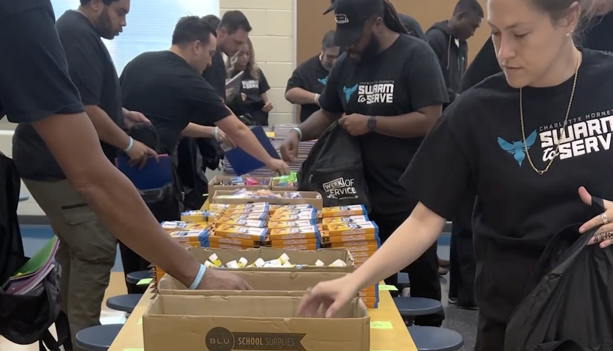  Charlotte Hornets employees build school supply backpacks for returning students.